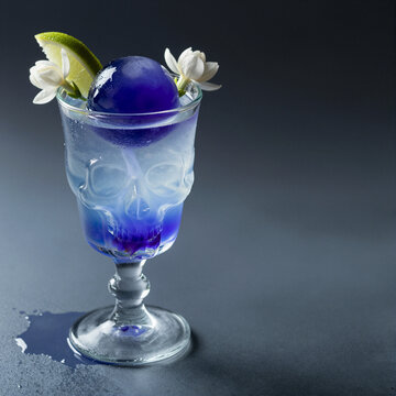 creative cocktail with skull glass and lime garnish on dark background with moody lighting