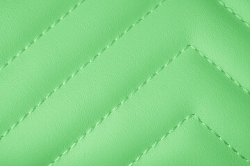 Fototapeta premium Vibrant lime green smooth textured padded fabric with intricate chevron quilted pattern close up surface