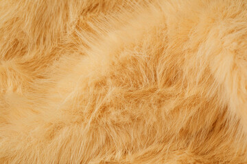 Soft fluffy light brown fur texture closeup making a warm cozy fabric material background © reddish