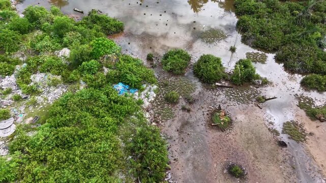 Aerial view of outdoor rubbish dump bordering marshland and vegetation.