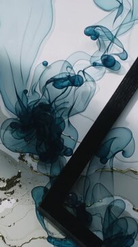 Vertical video: Rising teal dye plumes forming on table with gold streaks as black L tool entering
