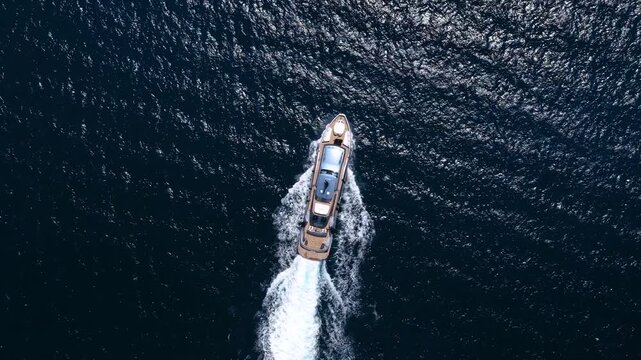 Aerial overhead view of a modern luxury yacht cruising over blue, sparkling ocean