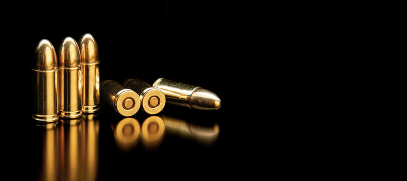 Group of 9mm pistol bullets with shiny golden brass shells isolated on a black back