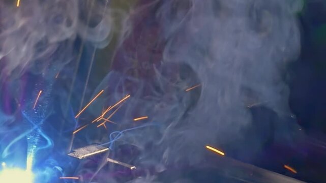 Witness the intricate dance of an industrial argon welding robot. Sparks fly and smoke swirls in mesmerizing slow motion, showcasing the power and precision of this modern technology.