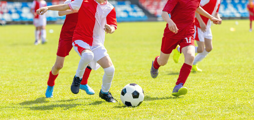 Naklejka premium Kids Soccer Match Action: Close-Up of Junior Football Players Chasing Ball on Field