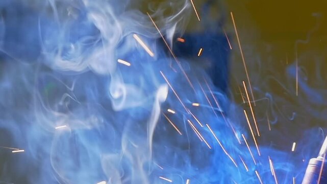 Experience the captivating dance of sparks and smoke as an industrial argon welding robot expertly fuses metal. Watch closely as the intricate details of welding come alive in mesmerizing slow motion.