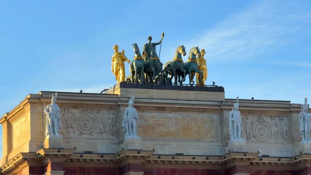 Golden quadriga statue glinting in the sun atop the Arc de Triomphe du Carrousel in Paris, France