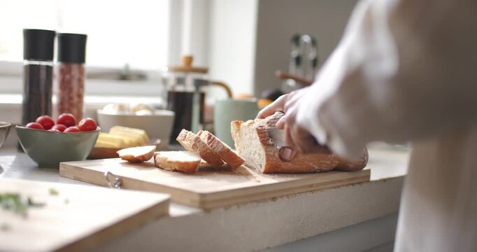 African American woman slicing loaf with knife, arranging slices on cutting board, making breakfast