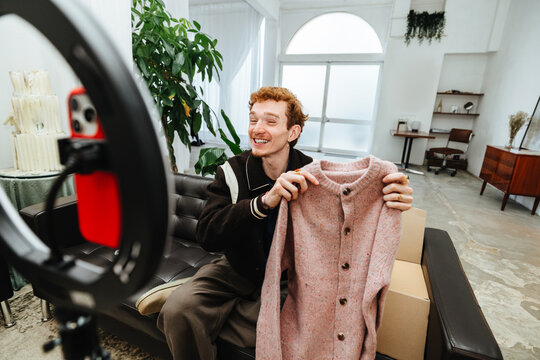 The camera captures a fashion seller as he presents clothing for online promotion.