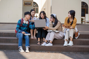 Fototapeta premium Diverse group of students working together on a laptop outside on a university campus