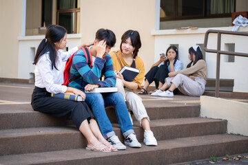 Fototapeta premium A diverse group of students actively discussing ideas while sitting on the steps of their campus outdoors
