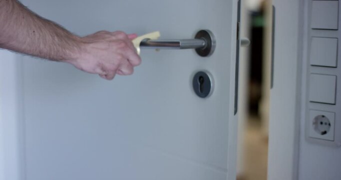 Close up of a hand hanging a brass hygiene touchless hook onto a wall mounted key rack