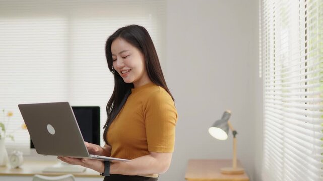 Smiling woman working on a laptop at home, ideal for remote work, home office, online business, productivity, digital work and professional lifestyle concepts.