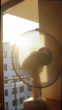 Electric fan cooling a room during an extreme summer heatwave at sunrise.