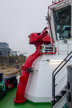 Firefighting Water Cannon System on Industrial Vessel Deck. Maritime Safety Equipment with Red Pipe and Monitor Nozzle on Ship in Harbor
