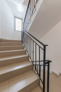 Modern stair case between floors. Stairs with metallic rail in modern building. Interior of a contemporary apartment or office building. Architecture and real estate background.