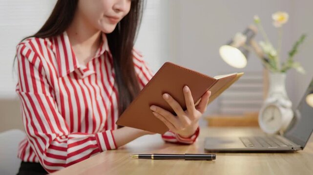 Woman working with a notebook and laptop at a desk, ideal for note taking, planning, productivity, study, office work, home office and professional lifestyle concepts.