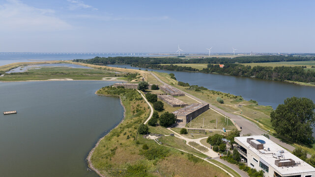 Aerial view of the Watersnoodmuseum featuring historic concrete caissons, surrounding green landscape, and calm water in Ouwerkerk, Zeeland, Netherlands.