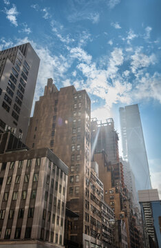 New york, usa august 19,2024. New york city skyscrapers rise over manhattan streets under a partly cloudy blue sky, sunlight streaming across glass and concrete