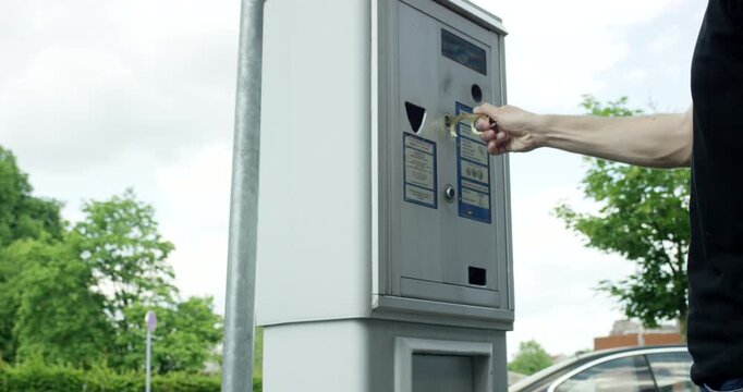 Close up of a man using a brass contactless tool to press a button on a parking ticket machine
