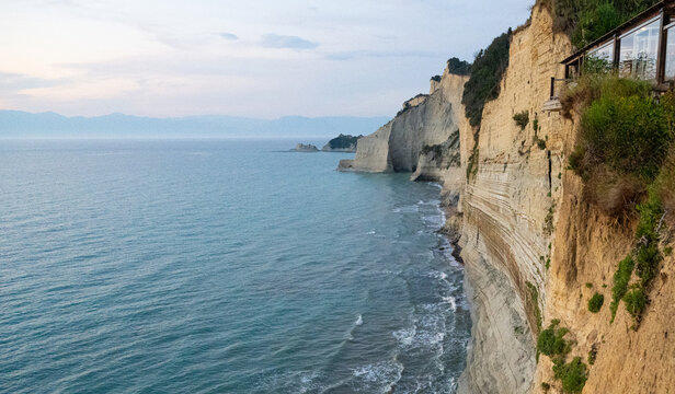 A serene and majestic view of the golden cliffs at Logas Beach in Corfu, evoking a deep sense of peaceful isolation, romantic wanderlust, and the calming beauty of a Mediterranean sunset escape.
