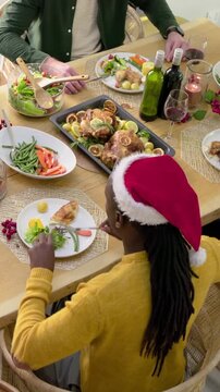 Vertical video: Plating Santa-hat host in yellow top at table serving beside roast turkey for toast