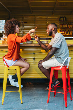 Young couple embracing the trend of Asian cuisine, happily eating noodles with chopsticks outdoors