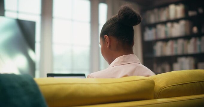 360 Degree. Black Woman Sits on a Home Couch Using a Laptop Computer to Shop Online, Browse Ecommerce Stores, Check Social Media, and Handle Digital Work Tasks Remotely. Cinematic Arc Tracking Shot.