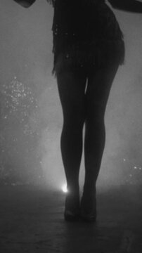 Old film twenties style happy girl dancing, black and white color, dark female silhouette 20s 30s. short vintage dress waving fly. retro woman dancer at party night club room full smoke sexy lond legs
