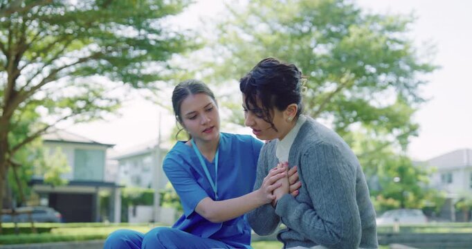 Nurse in Blue Scrubs Helping Woman with Chest Pain Outdoors &mdash; Heart Attack, Home Care, Emergency Medical Assistance in Park Setting