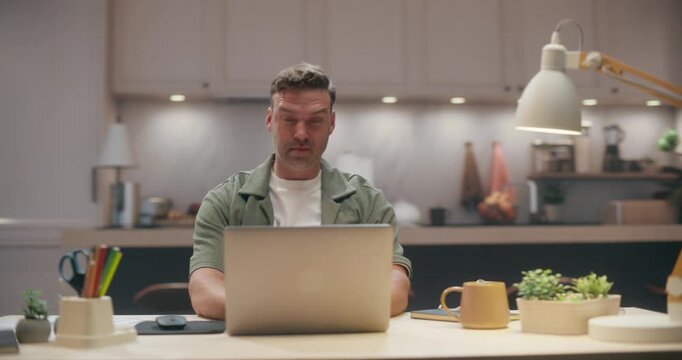 360 Degree. Caucasian Man Using Laptop Computer at Home Desk, Checking Email, Shopping Online and Handling Daily Remote Work Tasks Before Stretching to Relax in Modern Apartment. Arc Tracking Shot.