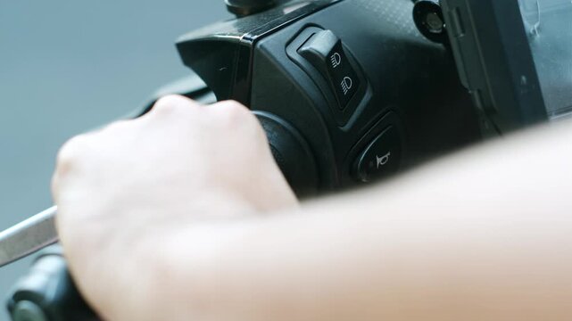 Close-up of hand pressing the horn button on motorcycle handlebar