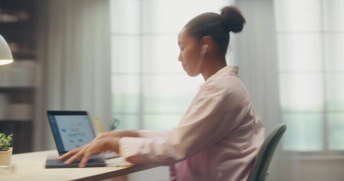 360 Degree Timelapse. Young Black Woman Sits at Home Desk Using Laptop Computer for Remote Work, Online Study and Writing Notes While Sipping Coffee and Listening to Music. Cinematic Arc Tracking Shot