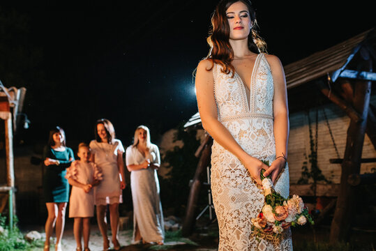 bride in a white dress throws a wedding bouquet