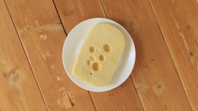 Dutch maasdam cheese slice rotating on a plate