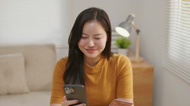 Happy woman using a credit card and smartphone to enjoy rewards, ideal for cashback, loyalty programs, online shopping, digital payment and personal finance concepts.
