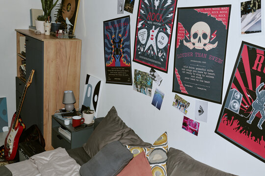 Wide angle shot of teenager bedroom featuring electric guitar, amplifier, music posters, decorated wall, expressing youth identity. Useful for lifestyle, interior, music culture marketing