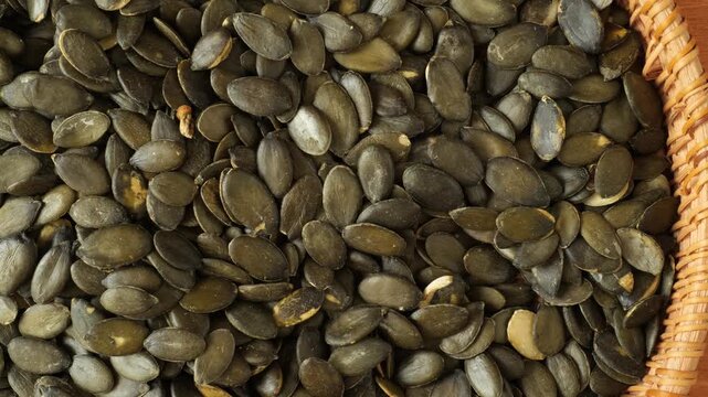 Healthy raw pumpkin seeds in a wicker basket slowly moving