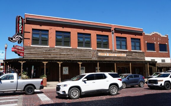 Fort Worth, Texas, U.S.A - June 1, 2026 - Historic Leddy Hand Made Boots storefront featuring large boot signage, saddlery branding, and parked vehicles along the Stockyards street.