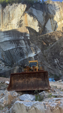 Old abandoned excavator inside a majestic rusty marble stone quarry