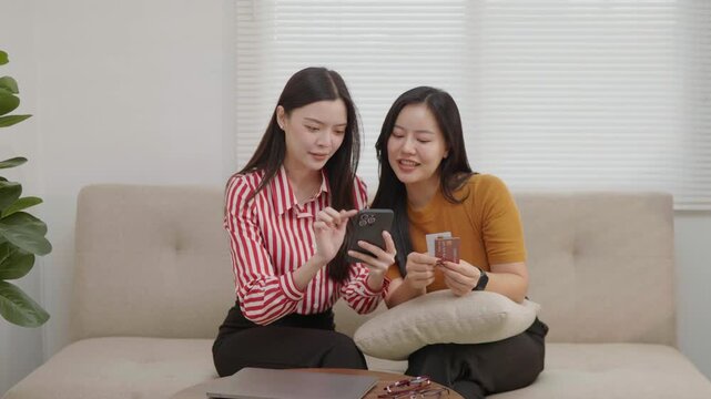 Two women using a credit card for online payment on a smartphone, ideal for e-commerce, mobile banking, digital transaction, online shopping and cashless payment concepts.