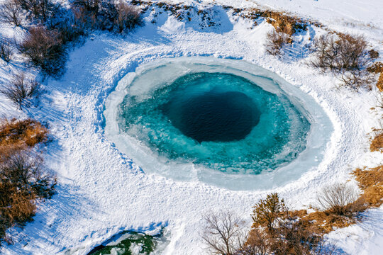 Aerial drone view circular ice hole frozen lake