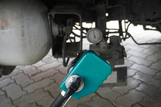 Teal Fuel Nozzle Connected to Vehicle CNG Tank