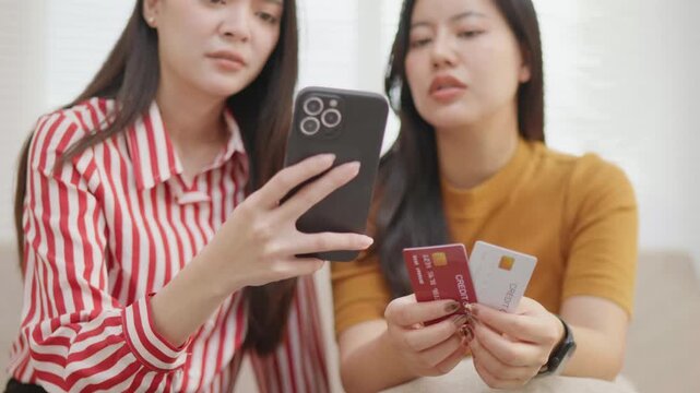 Two women stressed about credit card bills and debt, holding cards and smartphone, representing financial stress, overspending, budgeting problems and money anxiety.