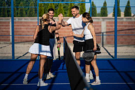 Padel team celebrating match victory with high five