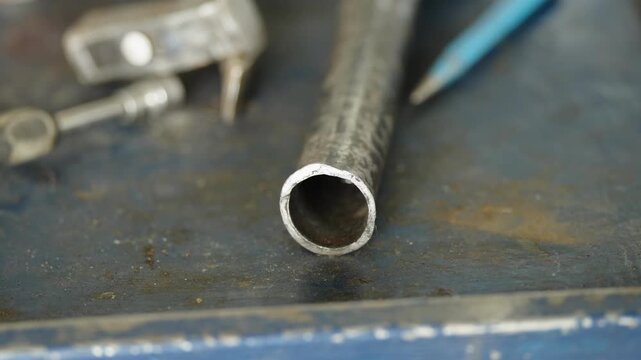 Close-up of a hollow metal pipe lying on a workbench in a workshop.