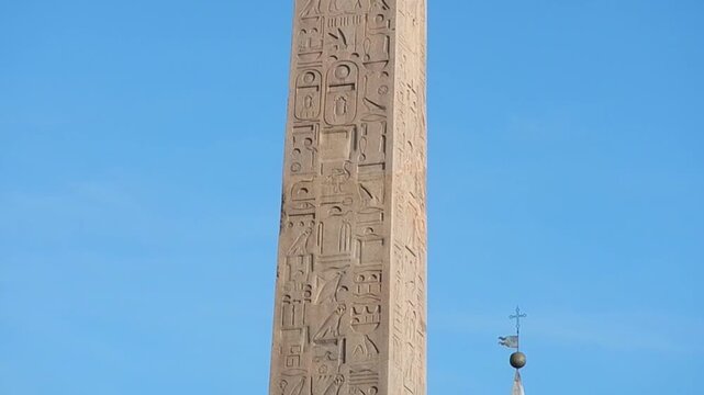 Lateran Obelisk, ancient Egyptian obelisk with Egyptian hieroglyphs, Christian cross with bird on blue sunny sky in Rome in Italy. Topics: antiquity, tourist attraction, archaeology, art, history