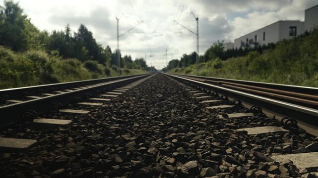 Empty train tracks under cloudy sky vanishing on the horizon