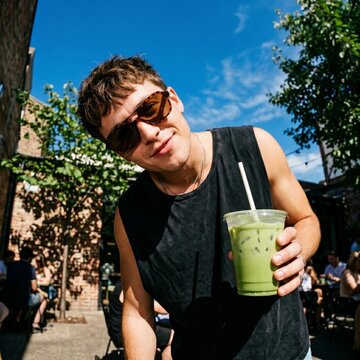 Young casual man enjoying a cold refreshing green matcha iced latte drink at an outdoor cafe