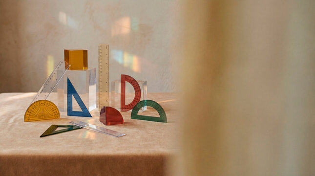 Translucent colored rulers and protractors arranged on a table with soft sunlight